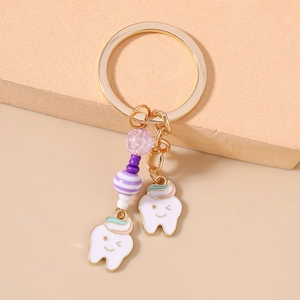Close-up of golden keychain with cute tooth charms and purple striped beaded details