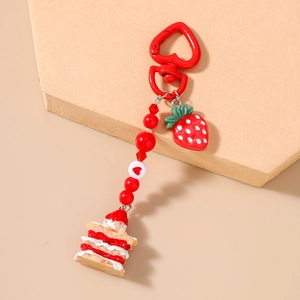 Close-up of a red strawberry cake keychain with heart beads and a simulation pendant