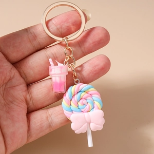 Close-up of colorful lollipop and ice cream keychain charms held by a hand