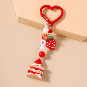 Detail of strawberry cake keychain with red heart clasp and beaded resin charms