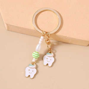 Detail of cute tooth charms with colorful beads on a gold metal keychain pendant