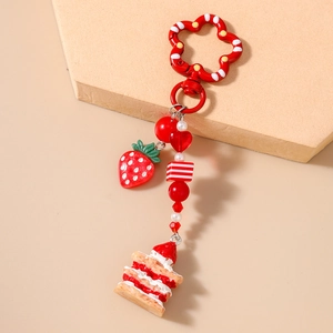 Detail of strawberry cake keychain with red heart beads and floral clasp for bags