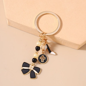 Détail du porte-clés doré avec nœud noir, escarpin blanc et pampille de perles