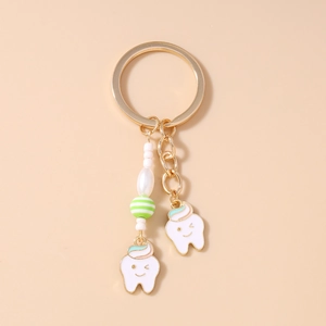 Detailed view of cute tooth charms with green striped bead on a gold keychain