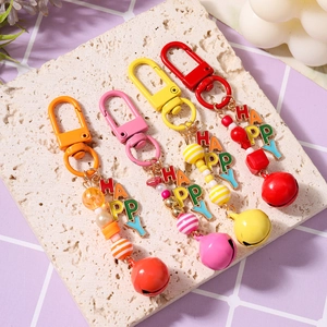 Colorful beaded HAPPY keychains with metal bells and alloy carabiners on a stone plate