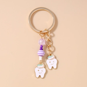 Detail of cute tooth charms with beaded chain on a gold fashion keychain for bags