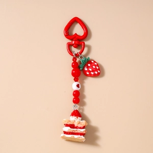 Macro shot of strawberry cake keychain with red heart clasp and beaded charms