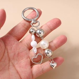 Detail of silver beaded heart keychain with white pearls and heart charms on a handbag