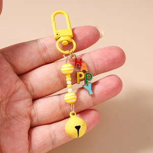 Detail view of colorful HAPPY letter charms and a yellow bell on a beaded keychain