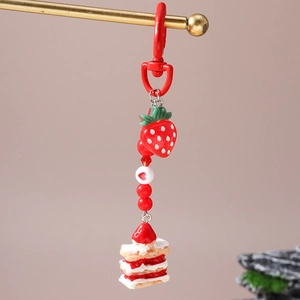 Detailed macro view of strawberry cake keychain with beaded charms and red lobster clasp