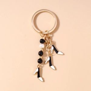 Détails des pendentifs de chaussures à talons noirs et blancs avec accents dorés et perles