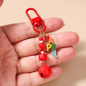 Detail of red beaded keychain with a metal bell and colorful HAPPY letter charms
