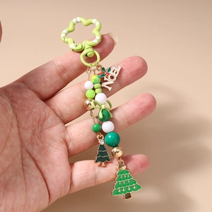 Detailed view of Christmas keychain with Noel tag and green enamel tree charms held in hand
