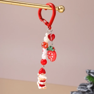 Detail of strawberry cake keychain with red heart beads and cute charms on a gold bar