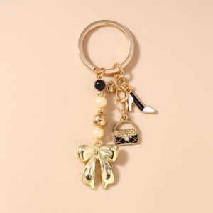 Vue détaillée d'un porte-clés doré avec nœud, pendentifs de chaussure et sac à main