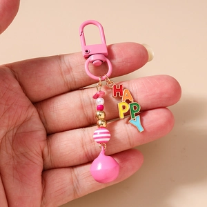 Close-up of pink beaded keychain with HAPPY metal charm and decorative tassels