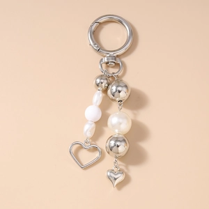 Detailed close-up of a silver heart keychain with pearl beads and polished metal charms