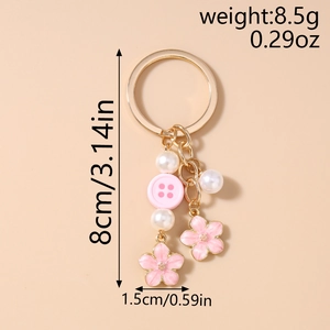 Detailed view of pink flower button keychain with gold chain and faux pearl accents