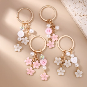 Golden cherry blossom keychain with heart charms and faux pearls on a beige background