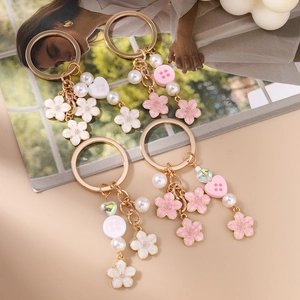 Sweet floral cherry blossom keychains with pearls and heart charms on a desk