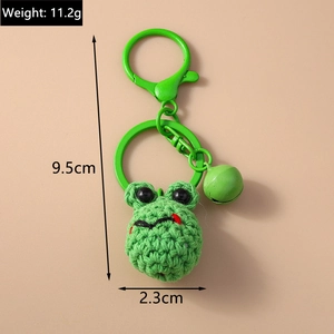Detailed close-up of a handmade green knitted frog keychain with metal bell and spring clip