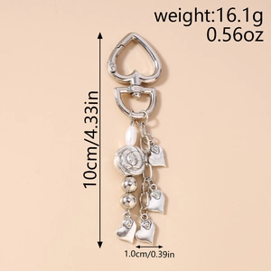 Detail view of heart-shaped clasp keychain with white pearls and flower charms