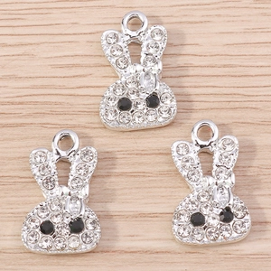 Trois breloques lapin serties de strass pour bijoux DIY sur fond de bois clair