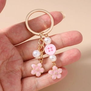 Detailed view of pink cherry blossom charms with white pearls on a gold-plated keychain