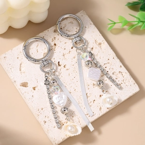 Silver beaded keychain with pearls, rhinestone chains, and shell heart pendants on stone