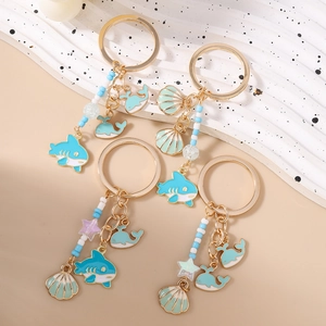 Marine charm keychain set featuring shark, whale, shell, and blue beaded tassels