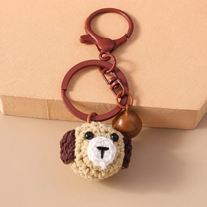 Close-up of handmade crochet puppy head keychain with brown bell and matte metal hook