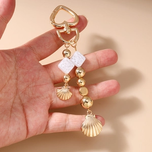 Détail du porte-clés perles et coquillages avec fermoir cœur doré et pendentifs