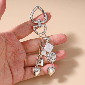 Detailed view of silver heart and flower charms on a beaded tassel keychain