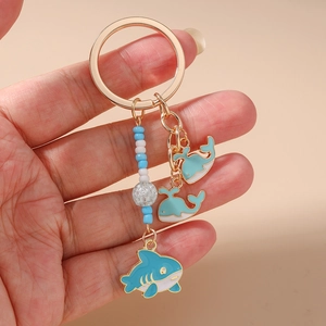 Detail of blue shark and whale charms with beaded chain on golden keychain ring