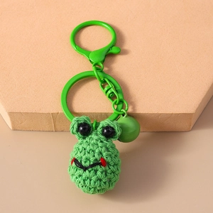 Close-up of handmade green crochet frog keychain with a mini bell and metal ring