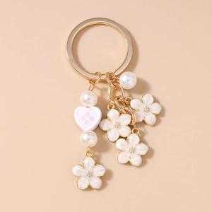 Detail of floral keychain with pearl accents and heart charm on a gold metal ring