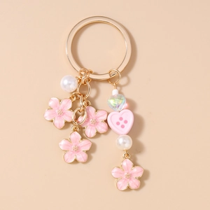 Detailed close-up of pink enamel cherry blossom keychain with gold alloy rings and pearls