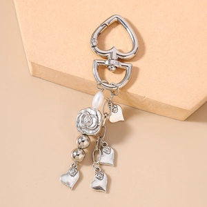 Detail of silver heart keychain featuring pearl drops and vintage rose flower charms