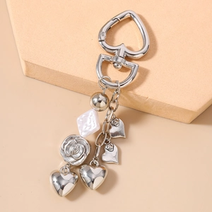 Detail view of heart clasp keychain with metallic rose, pearl and heart charms