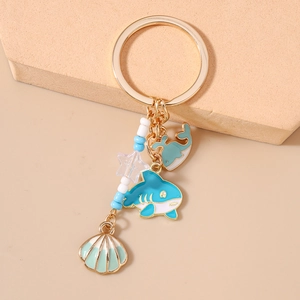 Detail of gold keychain with enamel shark, whale, beads, and seashell pendant charms
