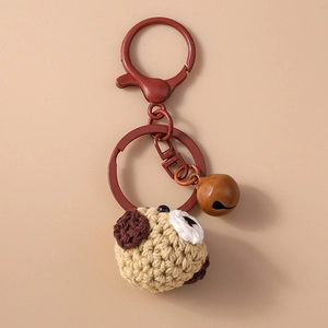 Detail view of handmade crochet puppy keychain with brown matte metal ring and small bell