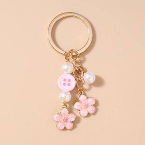 Close-up of pink enamel cherry blossom charms with imitation pearls on a gold keychain