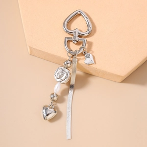 Detail of silver heart clasp keychain with rose charm, pearl, and snake chain tassels