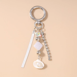 Detail of shell keychain with pearls, rhinestone chain and white ribbon on silver ring