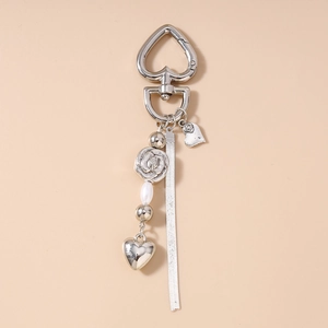 Detail of silver heart carabiner with rose bead, pearl, and metallic snake chain tassel