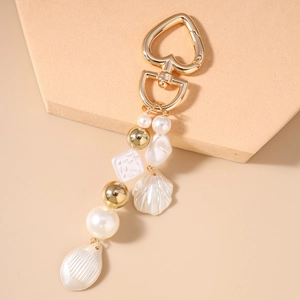 Détail du porte-clés en perles avec fermoir coeur doré et pendentif coquillage blanc