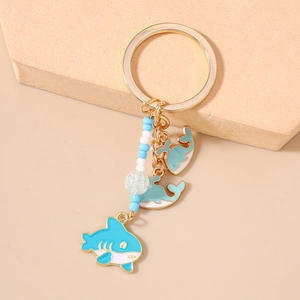 Detail of blue shark and dolphin enamel charms with handcrafted beads on a golden keychain