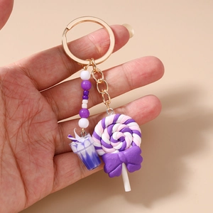 Detailed macro shot of a purple lollipop and mini drink cup charm on a gold keychain