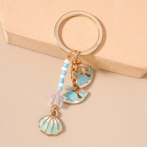 Detailed close-up of ocean-themed keychain with blue whale, shell and star charms