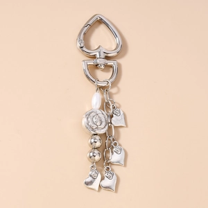 Detailed close-up of heart-shaped silver keychain with pearl beads and rose-engraved charms